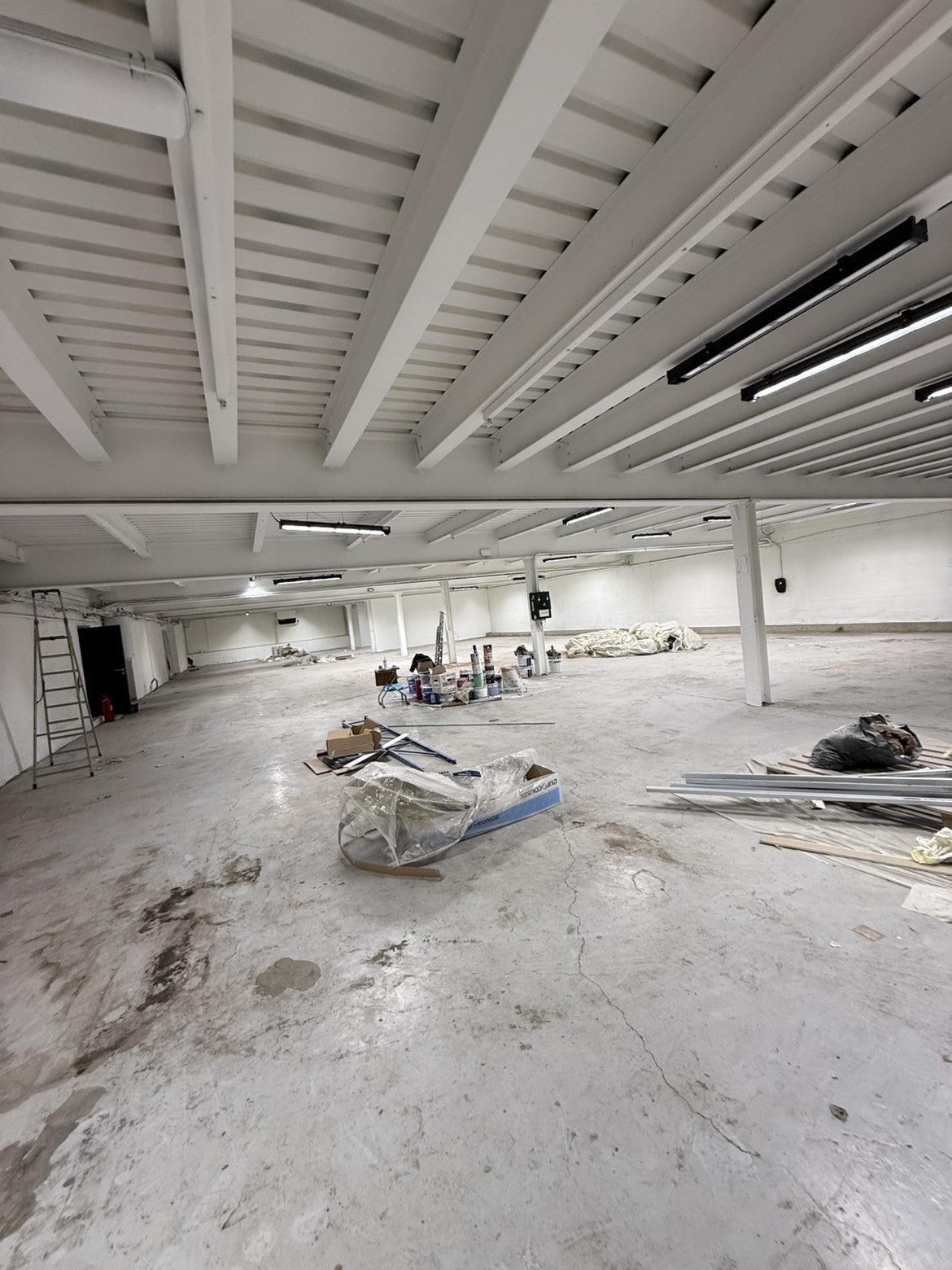 Grand plateau industriel avec poutres et plafond repeints en blanc